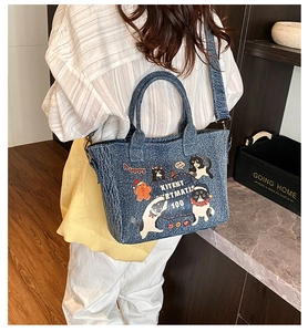 Detail of blue denim tote bag with cute cartoon cats and detachable crossbody strap