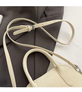 Detail of adjustable cream leather strap and silver buckle on a crossbody bag