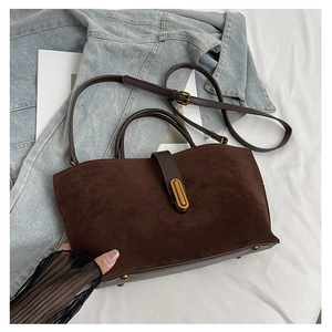 Detail view of brown suede tote bag with golden metal buckle and leather strap
