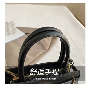 Close-up of elegant black tote bag with double top handles and golden metal zipper detail