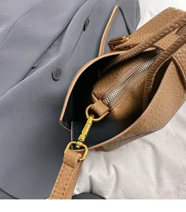 Close-up of brown litchi pattern leather tote bag with gold metal buckle and inner pouch