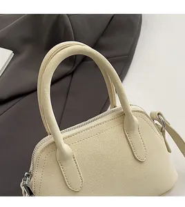 Detail of cream leather handbag with lychee grain texture and dual handle structure