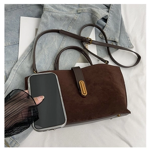 Detailed size comparison of a brown suede handbag with a smartphone and metal buckle