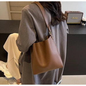 Close-up of brown litchi pattern leather tote bag showing texture and shoulder strap detail
