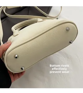 Detail of off-white handbag bottom showing four silver rivets for wear protection