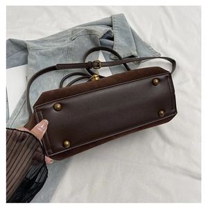 Detail of coffee brown leather bag base with vintage bronze metal feet and suede sides