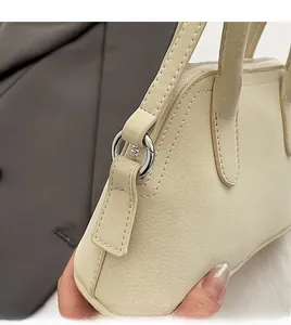 Detailed side view of beige leather handbag with premium silver metal zipper and D-ring