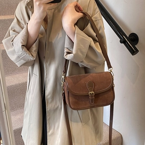 Chic retro dark brown frosted suede shoulder bag with metallic buckle on a beige coat