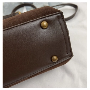 Detail of dark brown leather tote showing bottom gold rivets and stitching quality