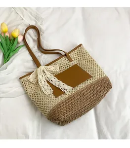 Détail d'un sac cabas en paille tissée avec poignées en cuir et nœud en dentelle blanche