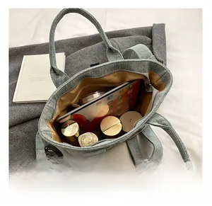 Interior view of light blue denim tote bag filled with iPad, cosmetics and accessories