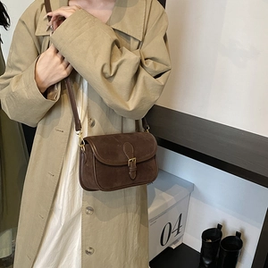 Retro brown suede saddle bag for women with flap and metal buckle worn by a model