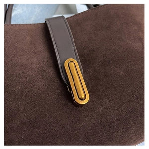 Macro detail of dark brown faux suede handbag featuring retro gold oval metal clasp closure