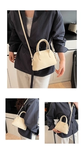 Detailed view of cream shell bag featuring pebble leather texture and protective metal studs