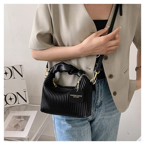 Close-up of black pleated leather handbag featuring golden zipper and brand tag detail