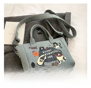 Detail of light blue denim tote with cartoon cat prints and adjustable wide shoulder strap