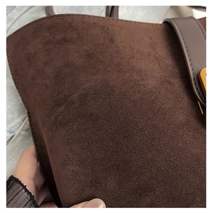 Close-up of brown suede tote bag showing fine matte texture and golden buckle detail
