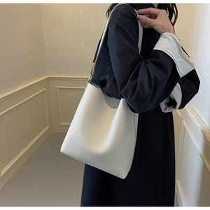 Close-up of white lychee-textured leather bucket bag showing grain detail and shoulder strap