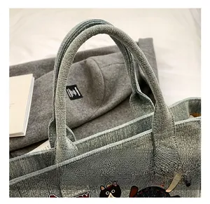 Detail of light blue denim tote bag featuring sturdy handles and cartoon cat prints