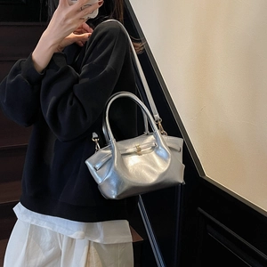 Détail d'un sac cabas argenté avec bandoulière dorée et poignée rigide