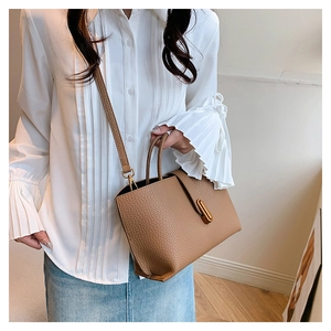 Detail of brown litchi pattern leather tote with golden bar metal buckle and shoulder strap