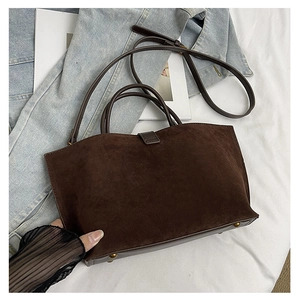 Detail of dark brown suede tote bag with metal base studs and adjustable strap