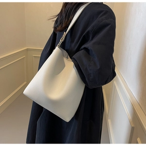 Detailed shot of white lychee grain leather bucket bag with wide shoulder strap