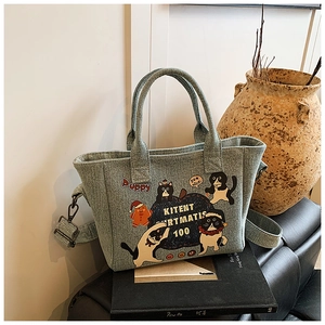 Close-up detail of cartoon cat illustrations and metal rings on a light blue denim tote bag