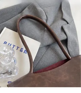 Detail eines glatten dunkelbraunen Lederriemens und roten Wildlederfutters der Tasche