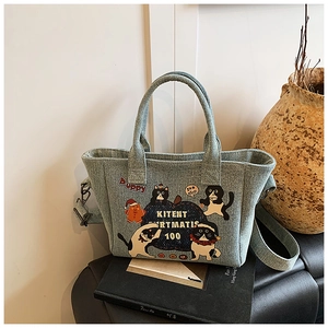 Detail of light blue denim tote bag with cat and dog cartoons on vintage books