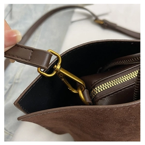 Detailed macro of vintage bronze clasp and premium mixed leather textures on a brown tote