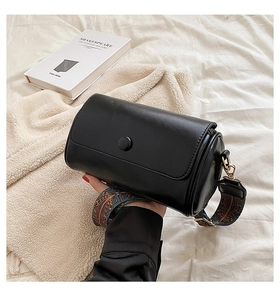 Close-up of black cylinder bag with colorful ethnic pattern wide shoulder strap detail