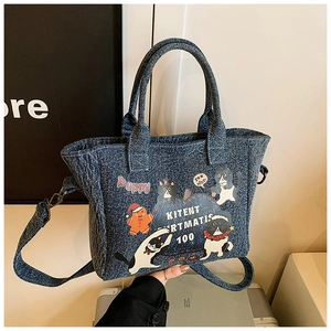 Close-up of denim tote bag featuring cartoon cat prints and detachable shoulder strap