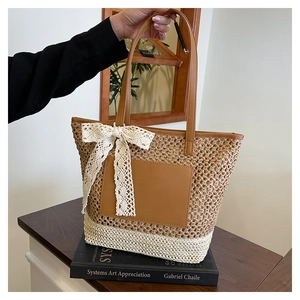 Detail of straw woven tote with brown leather pocket, long handles, and lace bow accent