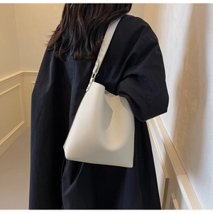 Detail of creamy white tote bag featuring premium lychee texture and adjustable leather strap