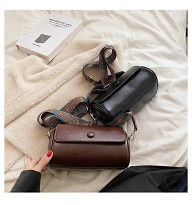 Close-up of retro cylinder pillow bags with bohemian style woven straps and metallic buckles