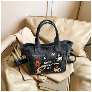 Close-up of cartoon denim tote with cat and gingerbread prints on a beige sofa