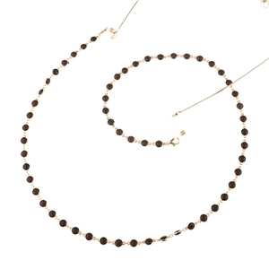 Chaîne de lunettes dorée avec perles brunes et boucles en silicone sur fond blanc