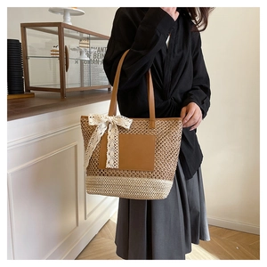 Detail of handmade woven tote bag with contrast straw pattern and lace bow accent