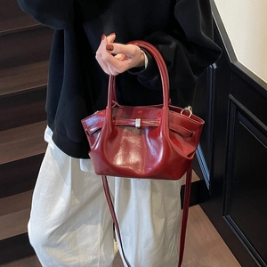 Détail d'un sac cabas bordeaux brillant en similicuir avec plis élégants et fermoir argent