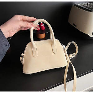 Detail of cream leather mini bag with cylindrical handles and adjustable shoulder strap