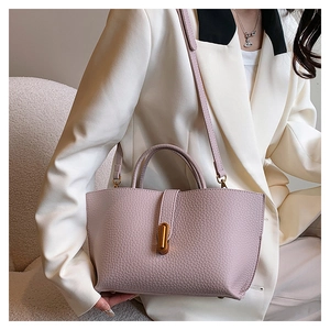 Detail of pink lychee grain leather tote bag with elegant golden cylindrical metal buckle