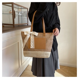Detail of hand-woven straw tote with dual-tone texture and a large white lace bow