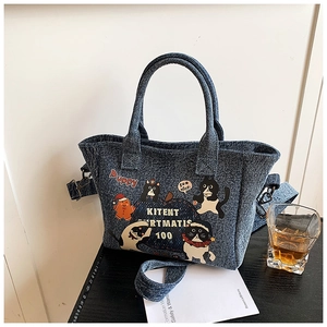 Close-up of denim tote bag featuring cartoon cat prints and fine fabric texture