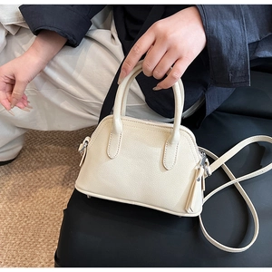 Detail of cream shell bag featuring pebble leather texture and silver hardware accents