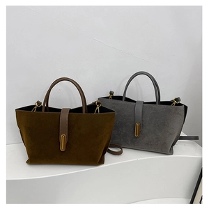 Detail view of suede tote bags in dark brown and gray with gold metal buckles