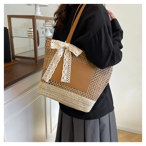 Close-up of woven straw tote bag featuring leather patch and white lace bow detail