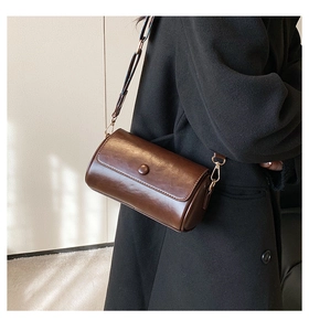 Detail of vintage dark brown leather cylinder bag with round decorative buckle and metal hook