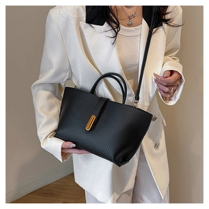Detail of black lychee leather tote bag with gold metal buckle and adjustable shoulder strap