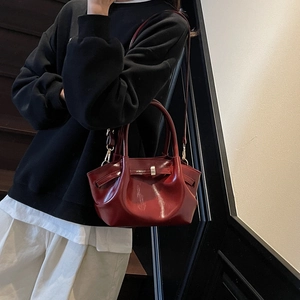 Détail macro du sac cabas en cuir ciré rouge foncé avec poignée et fermoir en métal